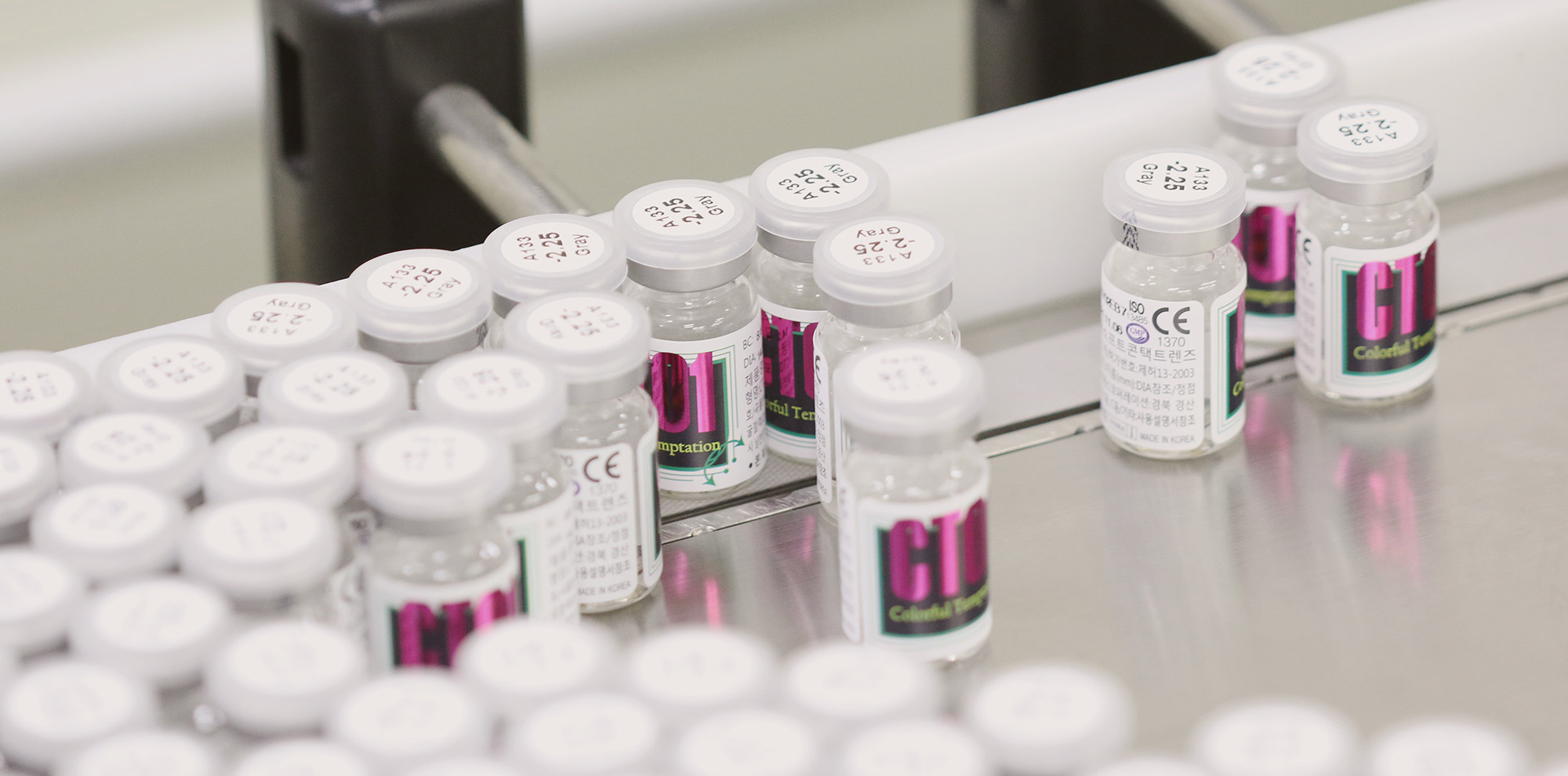 Labeled contact lens vials moving through a packaging line